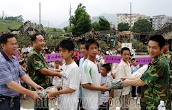 昭平县人武部、武警中队、县民政局领导为洪灾后的城东中学学生发放衣物。