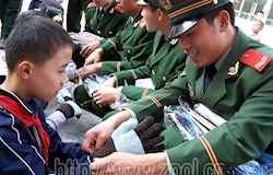 即将退伍的武警老兵为贫困学生戴上御寒用的手套。